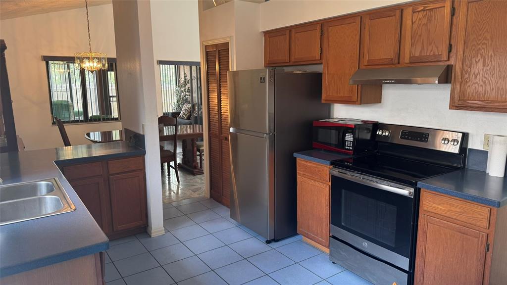 A kitchen with wood cabinets, blue countertops, stainless steel appliances, and light-colored tile flooring — 265 RIVER CHASE DRIVE, ORLANDO, FL