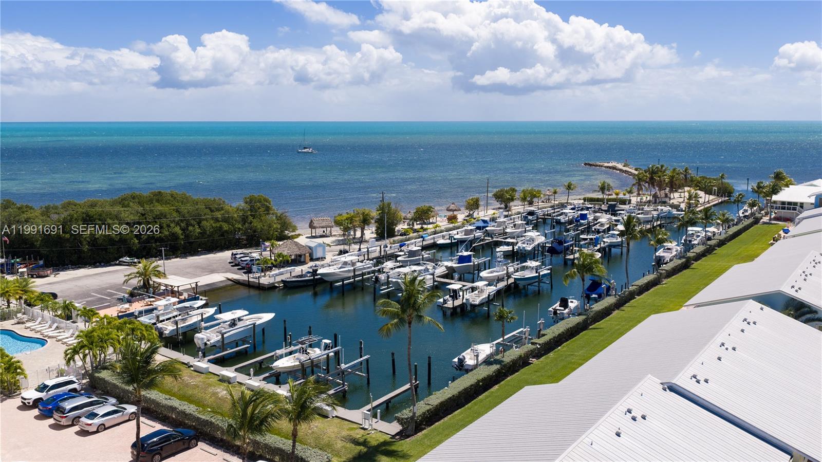An aerial view shows a marina with numerous docked boats, palm trees, and coastal buildings — 1500 Ocean Bay Dr # F5, Key Largo FL 33037, KEY LARGO, FL
