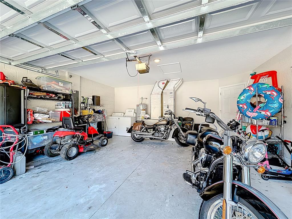 A garage contains two motorcycles, a riding lawn mower, laundry appliances, and various storage items — 6188 E SENECA STREET, INVERNESS, FL