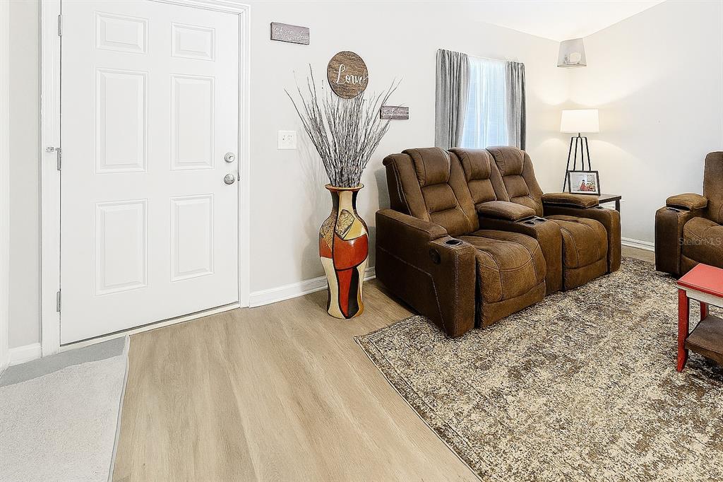 A living room features light wood flooring, a brown reclining sofa, and a decorative floor vase — 6188 E SENECA STREET, INVERNESS, FL