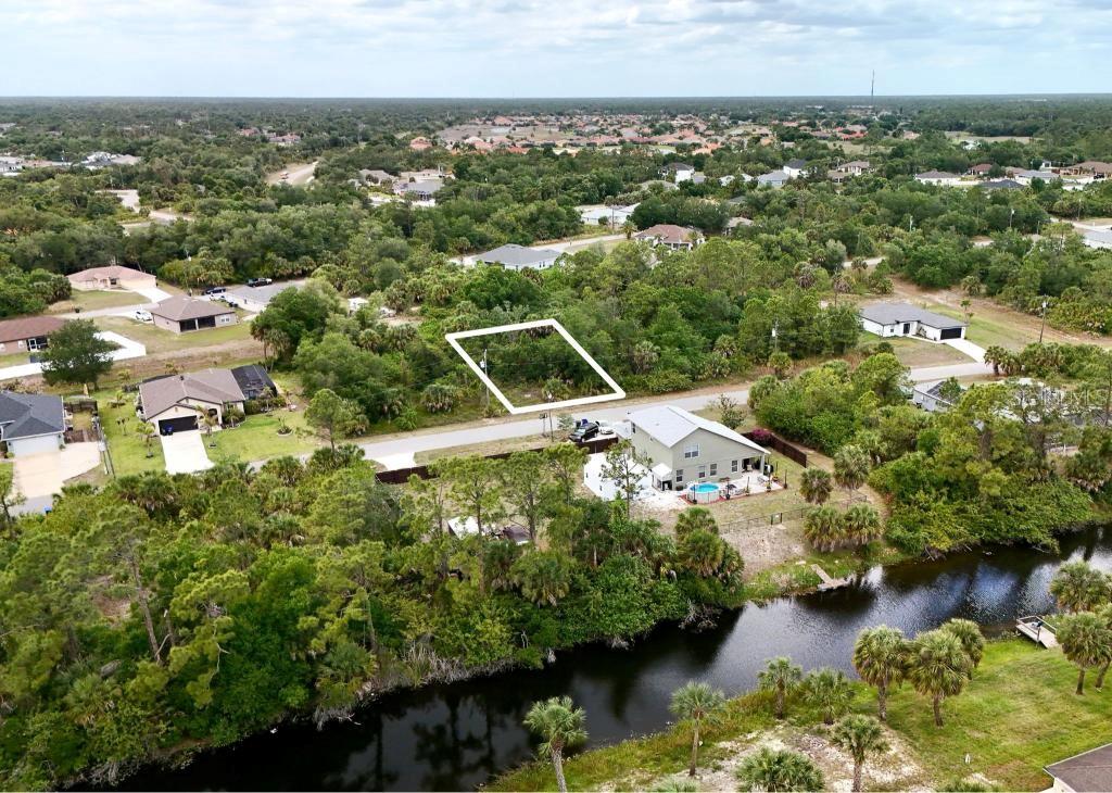 An aerial view shows a vacant, rectangular lot outlined in white amidst a wooded neighborhood — KISKA ROAD, NORTH PORT, FL