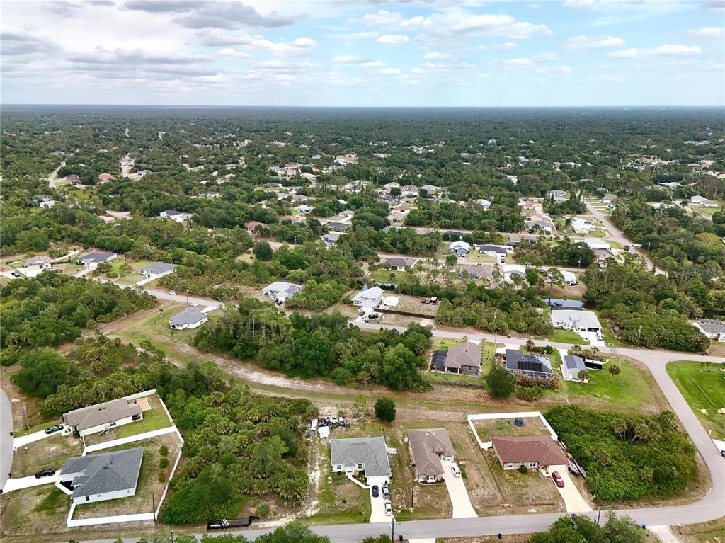 An aerial view shows a suburban neighborhood with scattered houses surrounded by dense green vegetation — KISKA ROAD, NORTH PORT, FL