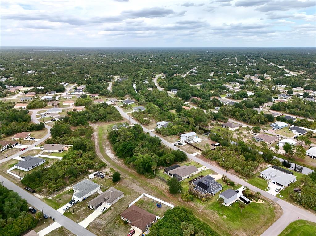 An aerial view shows suburban houses scattered among dense trees and vegetation under a cloudy sky — KISKA ROAD, NORTH PORT, FL