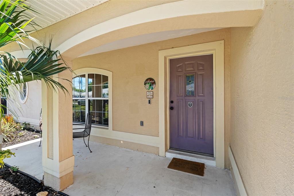 A covered front porch features a purple front door and a small window — 34 BEAVERDAM LANE, PALM COAST, FL