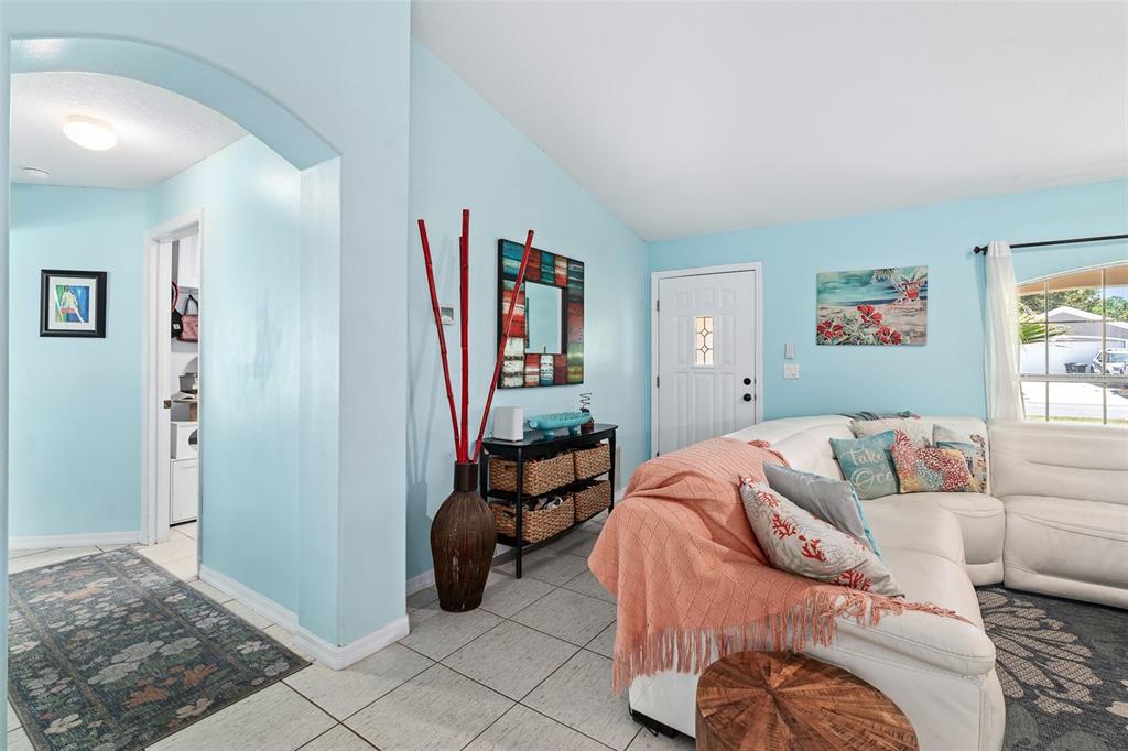 A living room features light blue walls, tile flooring, and a white sectional sofa — 34 BEAVERDAM LANE, PALM COAST, FL