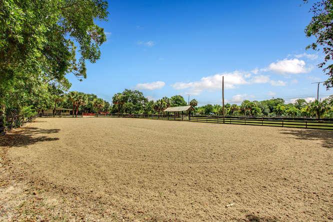 A large, fenced-in dirt riding arena sits under a clear blue sky — 2833 F Road, FL 33470, FL