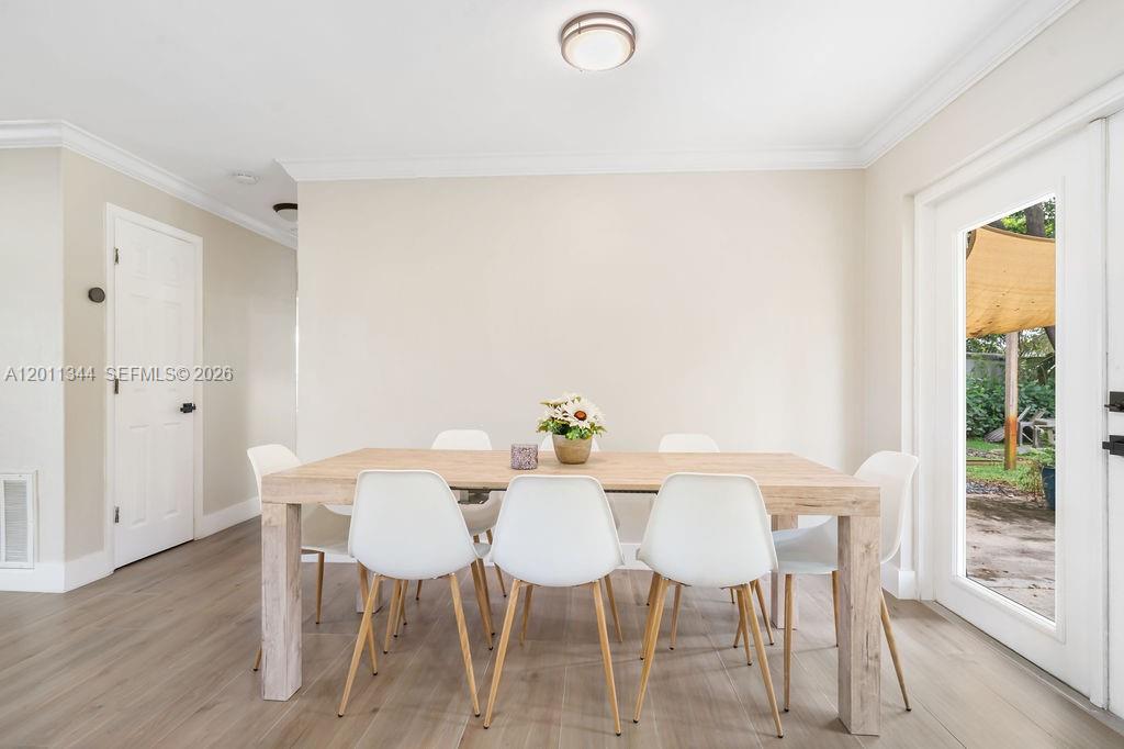 A dining room features a light wood table, white chairs, and a glass door — 913 Lighthouse Dr, North Palm Beach FL 33408, NORTH PALM BEACH, FL