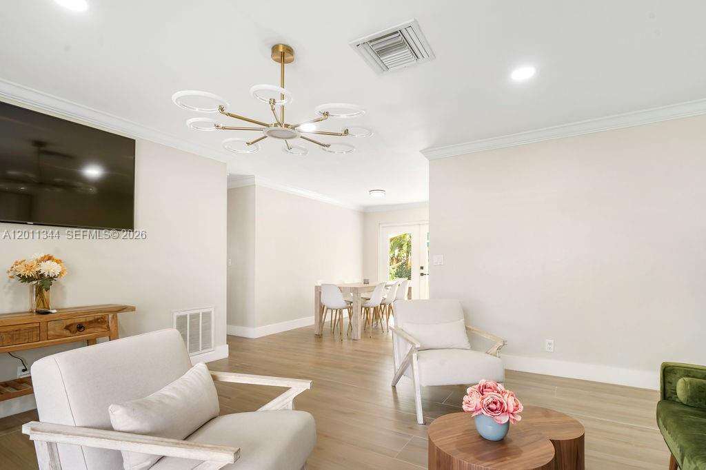 A living room with light wood floors, a modern chandelier, and a dining area beyond — 913 Lighthouse Dr, North Palm Beach FL 33408, NORTH PALM BEACH, FL