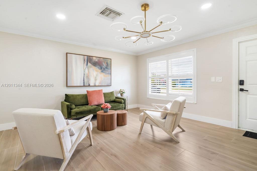 A living room features a green sofa, two armchairs, a modern chandelier, and wood flooring — 913 Lighthouse Dr, North Palm Beach FL 33408, NORTH PALM BEACH, FL