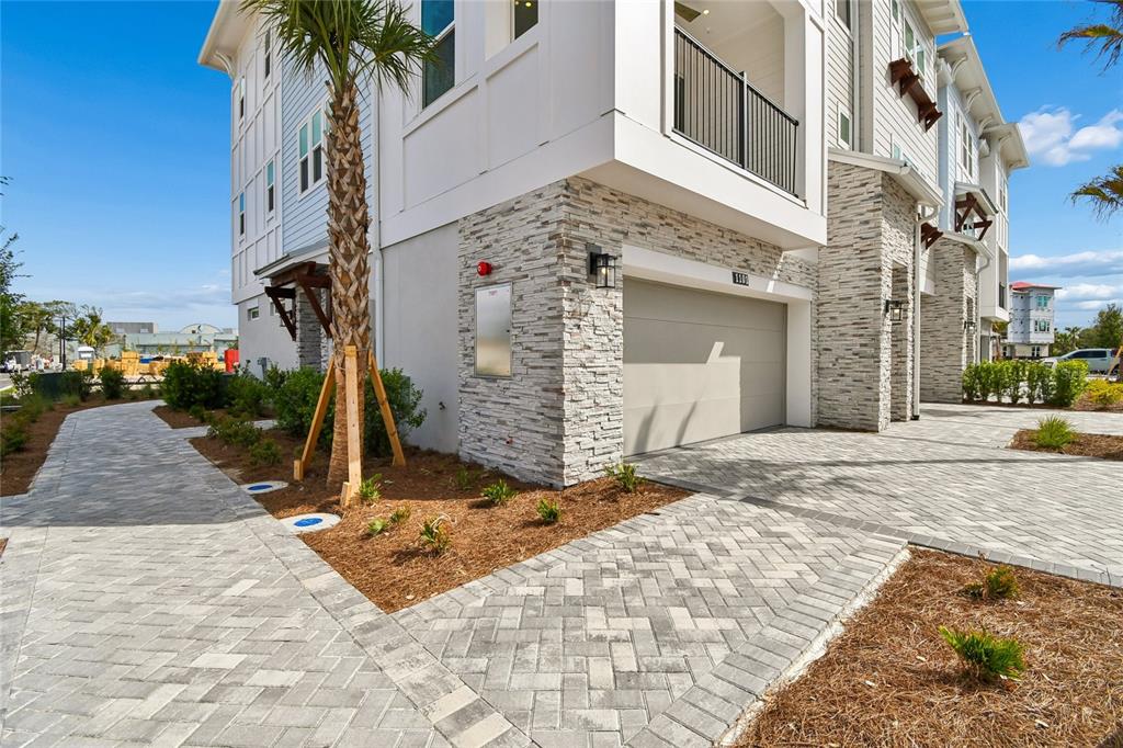 A multi-story building exterior features a stone facade, a garage, and a paved walkway — 2101 TIDEWATCH LOOP, NEW SMYRNA BEACH, FL