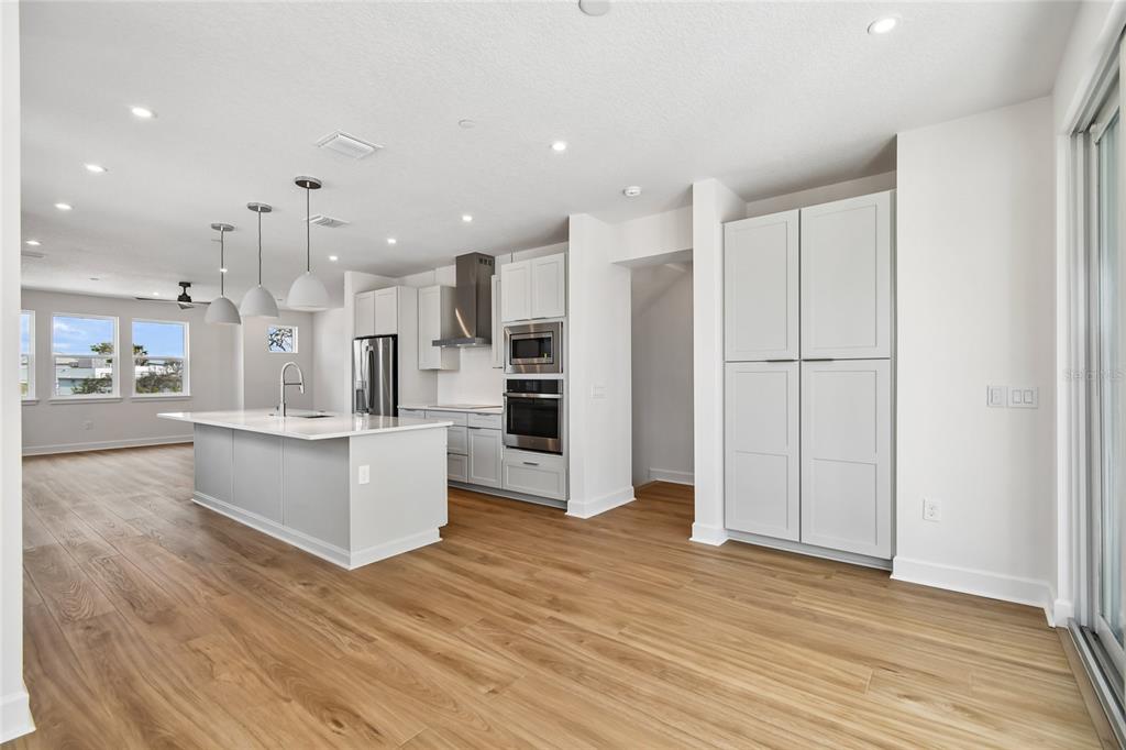 A modern kitchen features light gray cabinetry, a central island, and wood-look flooring — 2101 TIDEWATCH LOOP, NEW SMYRNA BEACH, FL