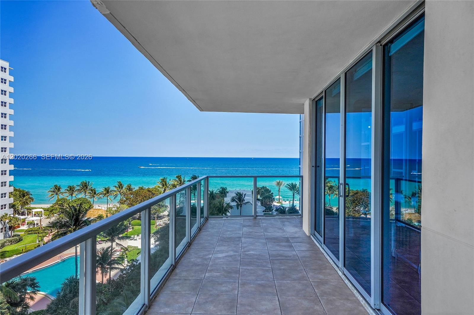 A balcony with tile flooring and a glass railing overlooks the ocean and pool — 3101 S Ocean Dr # 701, Hollywood FL 33019, HOLLYWOOD, FL