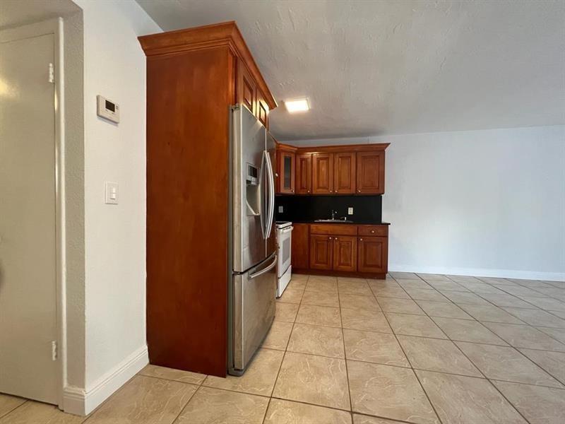 A kitchen features wood cabinets, stainless steel appliances, and light-colored tile flooring — 7851 Dunham Boulevard # 4, Miami FL 33138, MIAMI, FL