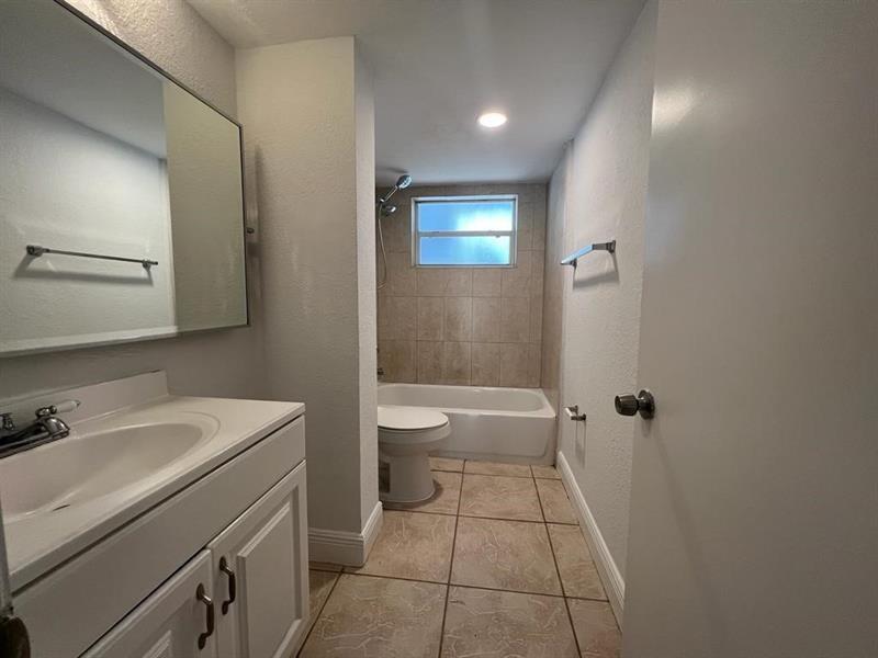 A bathroom features a white vanity, a toilet, and a tiled shower-tub combination — 7851 Dunham Boulevard # 4, Miami FL 33138, MIAMI, FL