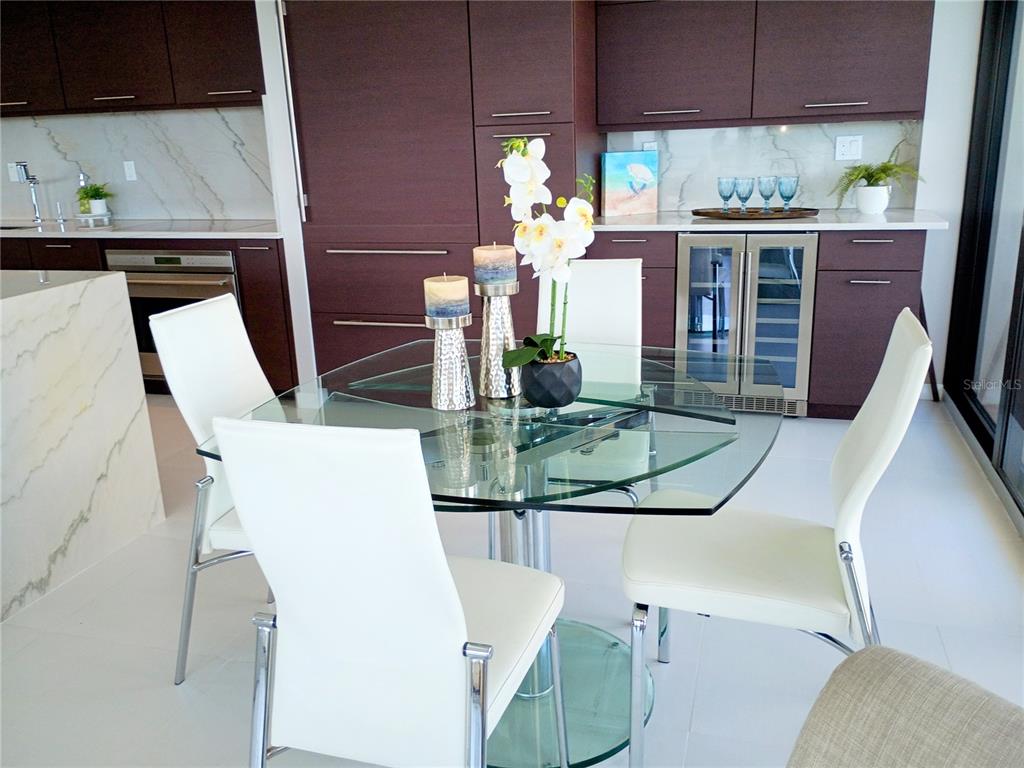 A modern dining area features a glass table with white chairs and dark cabinetry — 2900 N ATLANTIC AVENUE UNIT 2001, DAYTONA BEACH, FL