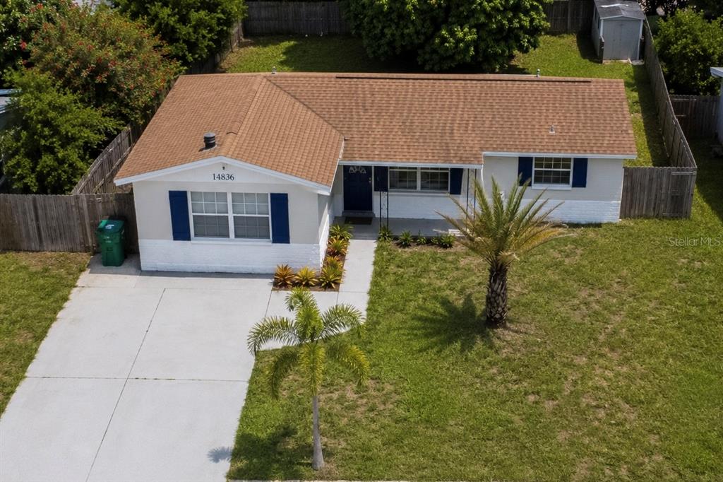 An aerial view shows a single-story house with a brown roof, white siding, and blue shutters — 14836 55TH WAY N, CLEARWATER, FL