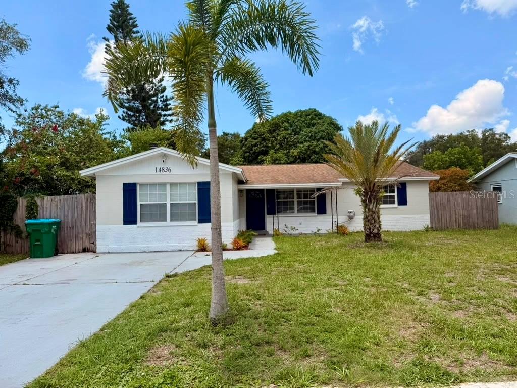 A single-story house with a light-colored exterior, blue shutters, and a palm tree in front — 14836 55TH WAY N, CLEARWATER, FL