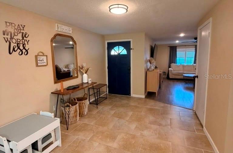 An entryway with tile flooring leads to a living room with a sofa and windows — 14836 55TH WAY N, CLEARWATER, FL