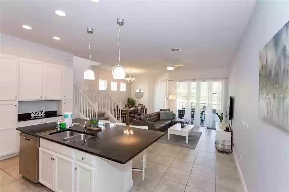 An open-concept kitchen with a dark granite island overlooks a living and dining area — 134 CAPTIVA DRIVE, DAVENPORT, FL