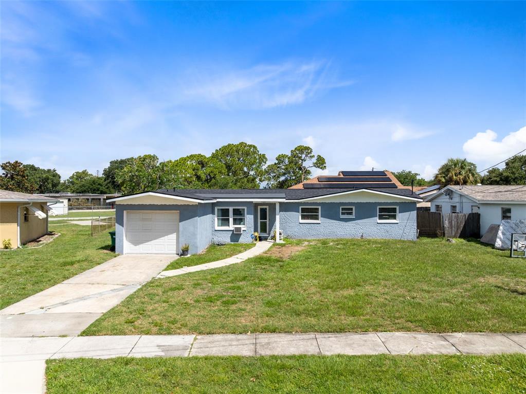 A single-story blue house with a white garage door, concrete driveway, and a grassy lawn — 920 GARDEN ROAD, MERRITT ISLAND, FL