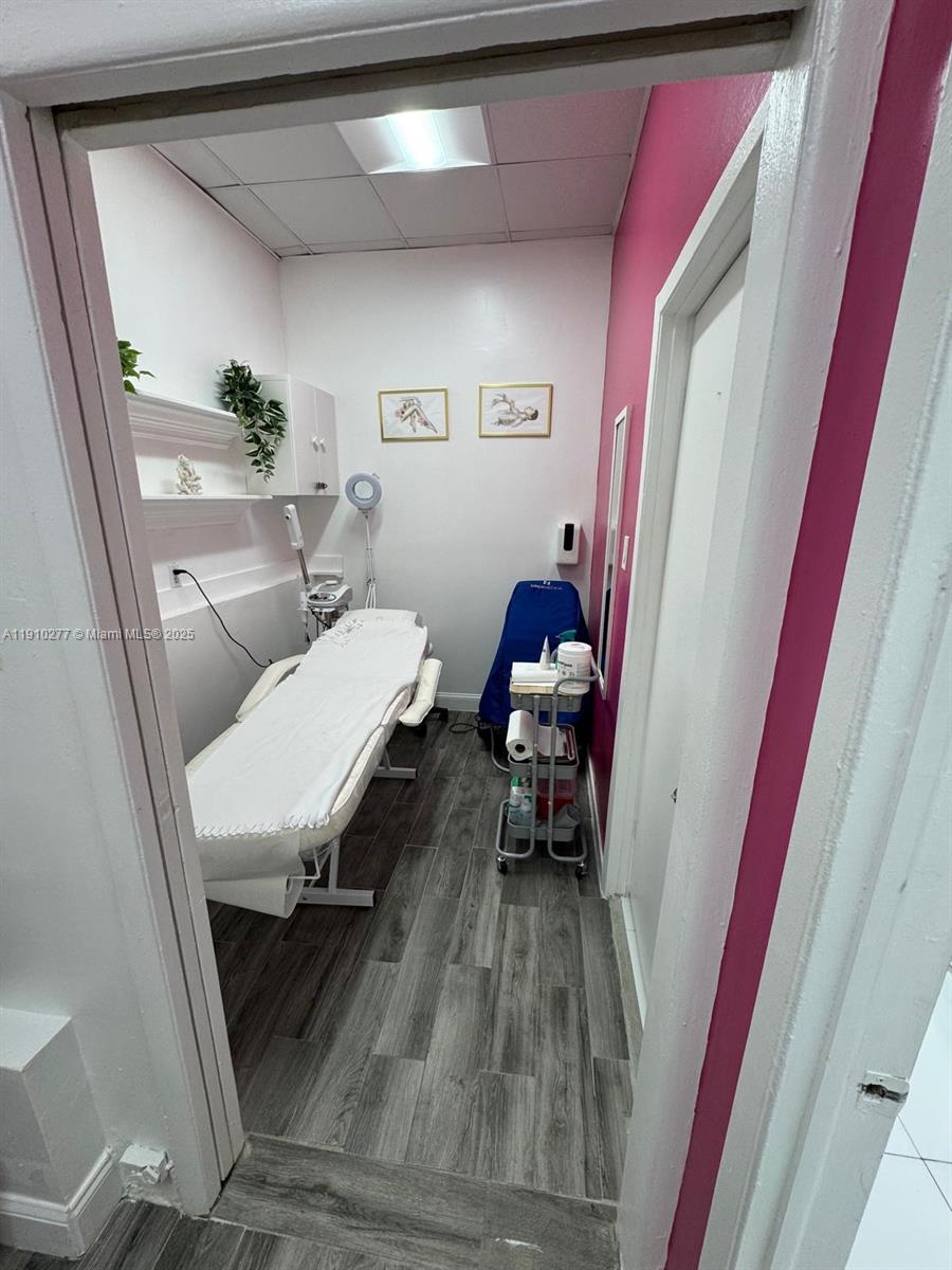 A small treatment room features a white massage table, wood-look flooring, and pink accent walls — BAY HARBOUR, Bay Harbor Islands FL 33154, BAY HARBOR ISLANDS, FL