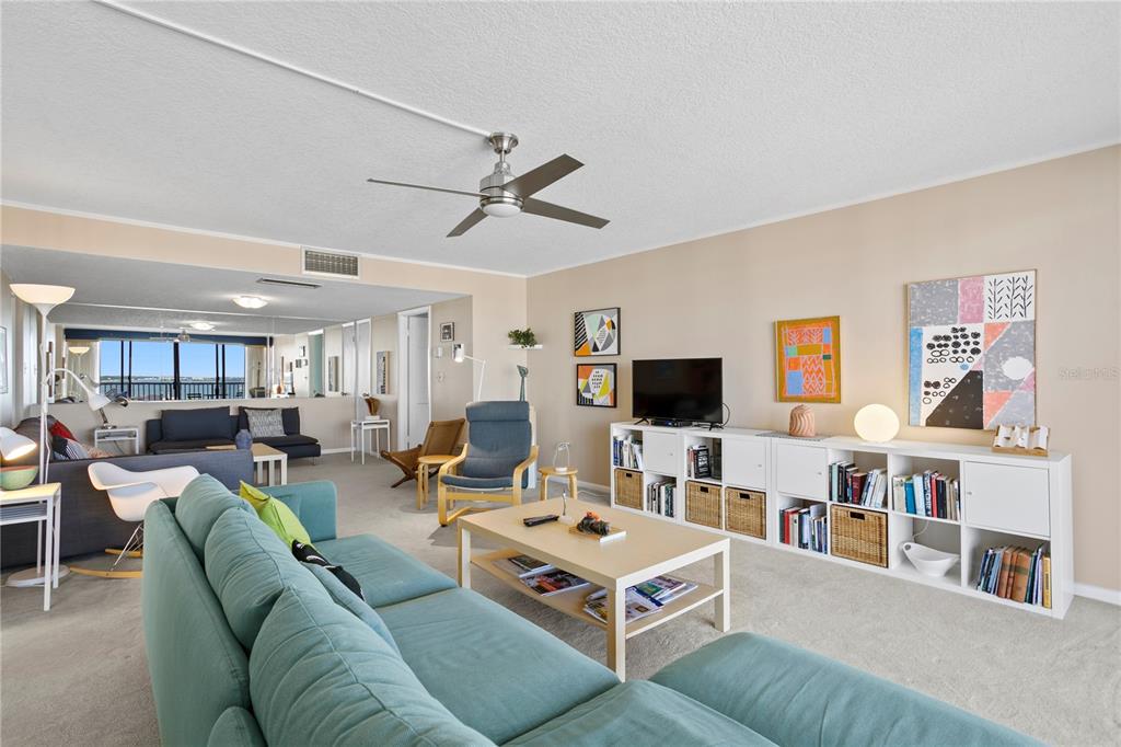 A living room features a teal sofa, a light wood coffee table, and white shelving — 450 TREASURE ISLAND CAUSEWAY UNIT 702, TREASURE ISLAND, FL