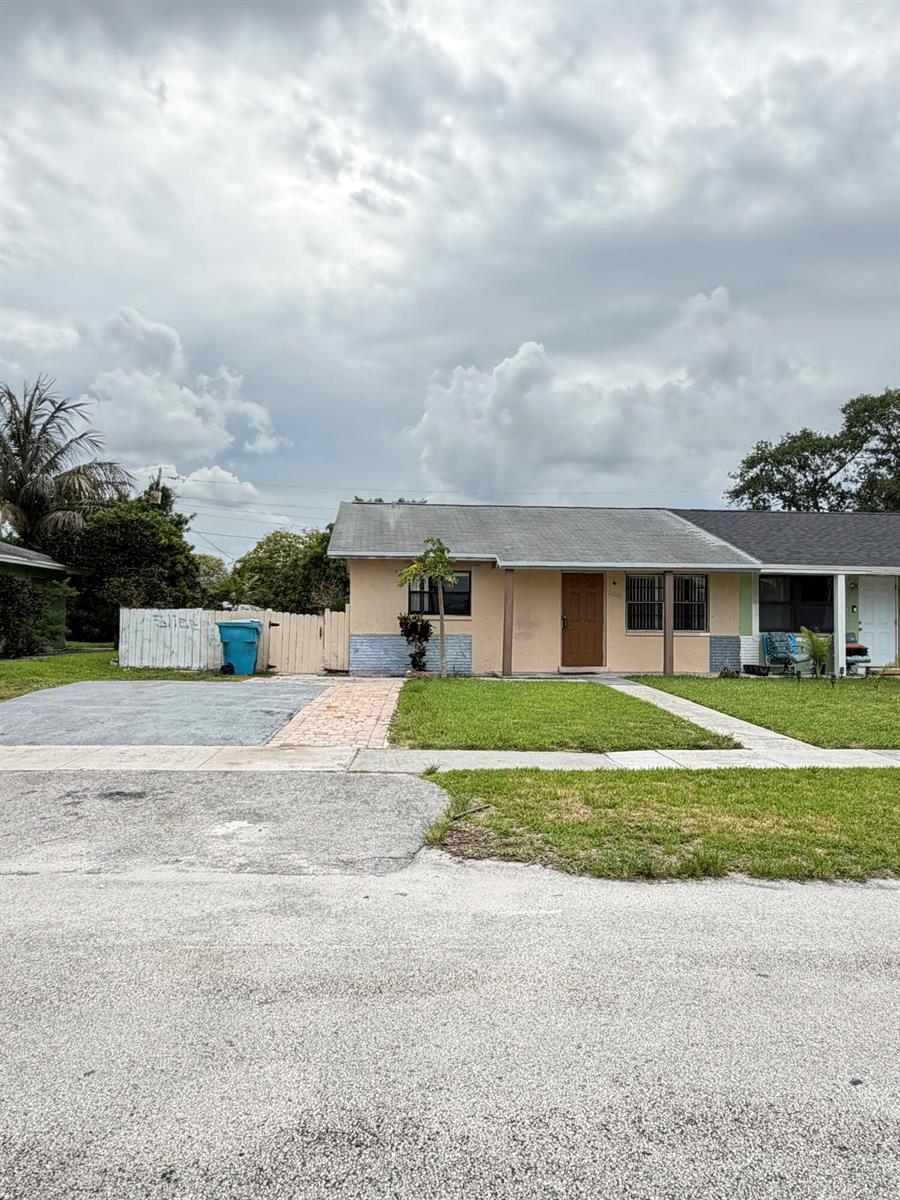 A single-story duplex with a tan exterior, a brown front door, and a paved driveway — 3243 Grove Road, Boynton Beach FL 33435, BOYNTON BEACH, FL