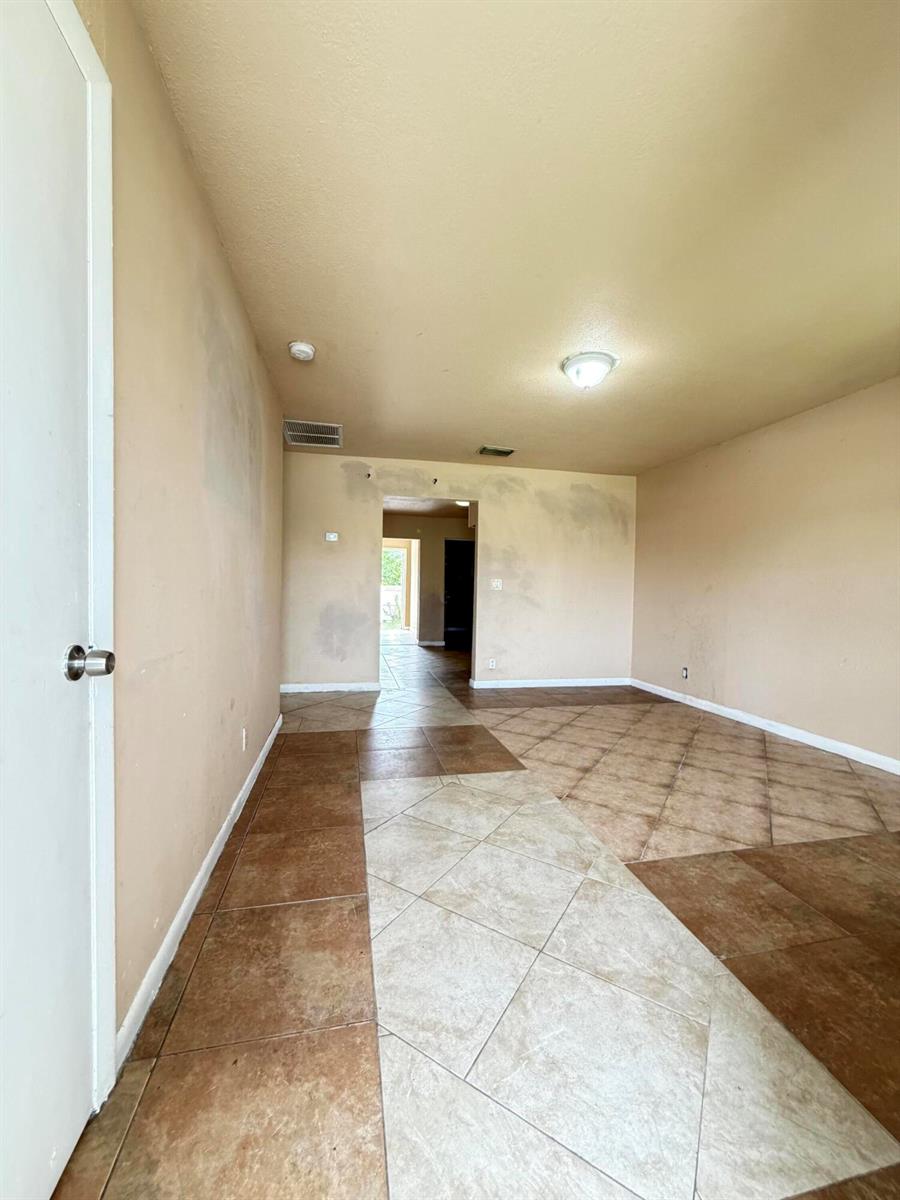 An empty room with tan walls and a two-tone diagonal tile floor — 3243 Grove Road, Boynton Beach FL 33435, BOYNTON BEACH, FL