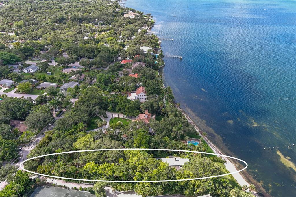An aerial view shows a waterfront property with a house surrounded by dense trees — 3301 BAY SHORE ROAD, SARASOTA, FL