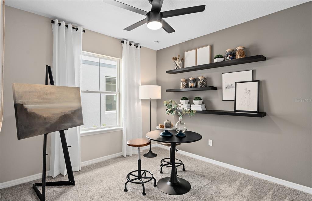 A home office features a black pedestal table, two stools, floating shelves, and an art easel — 10740 LEAFY LAUREL STREET, ORLANDO, FL