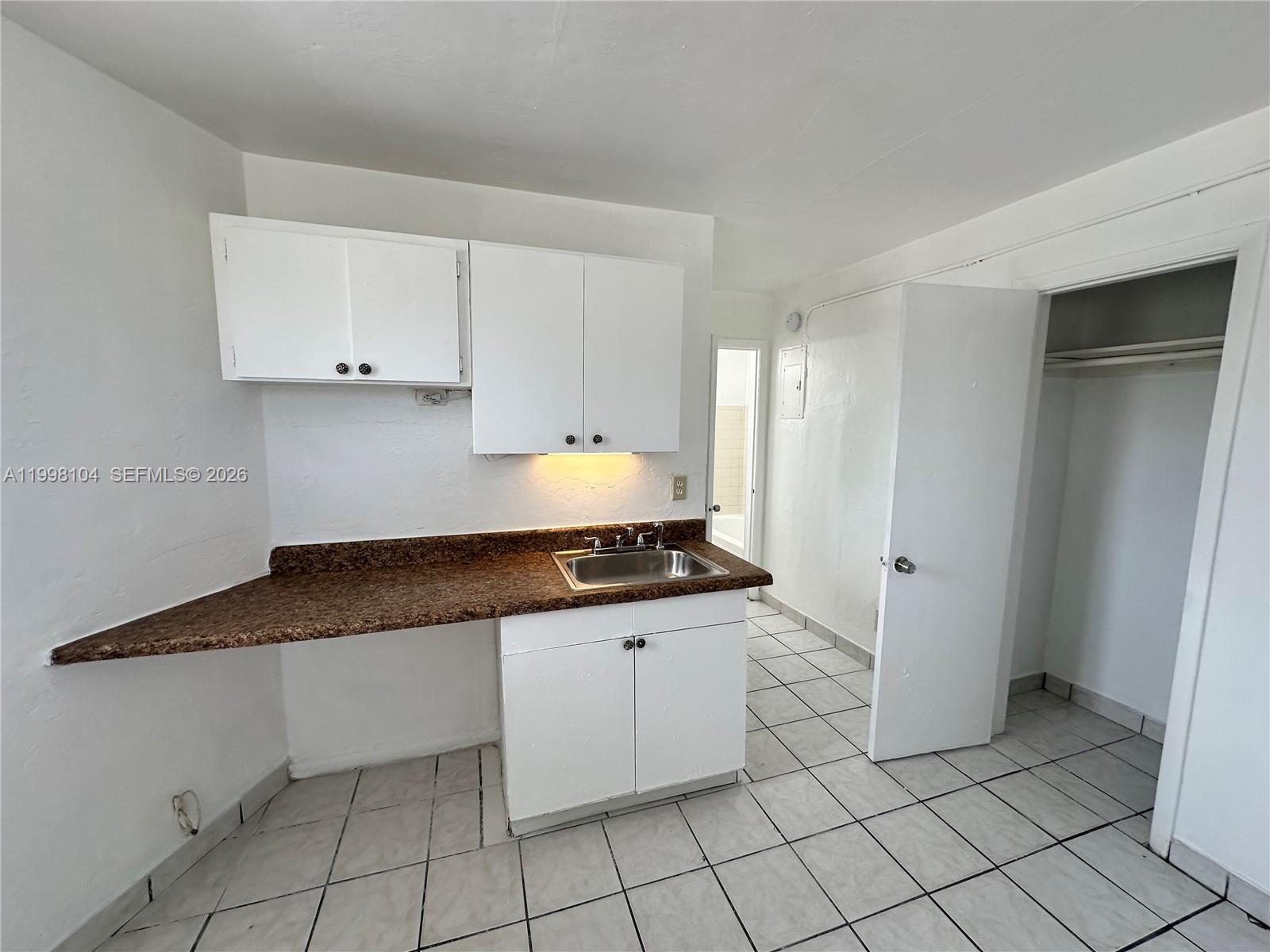 A small kitchen features white cabinets, a brown laminate countertop, and a stainless steel sink — 701 NW 7th Ave # 1, Hallandale Beach FL 33009, HALLANDALE BEACH, FL