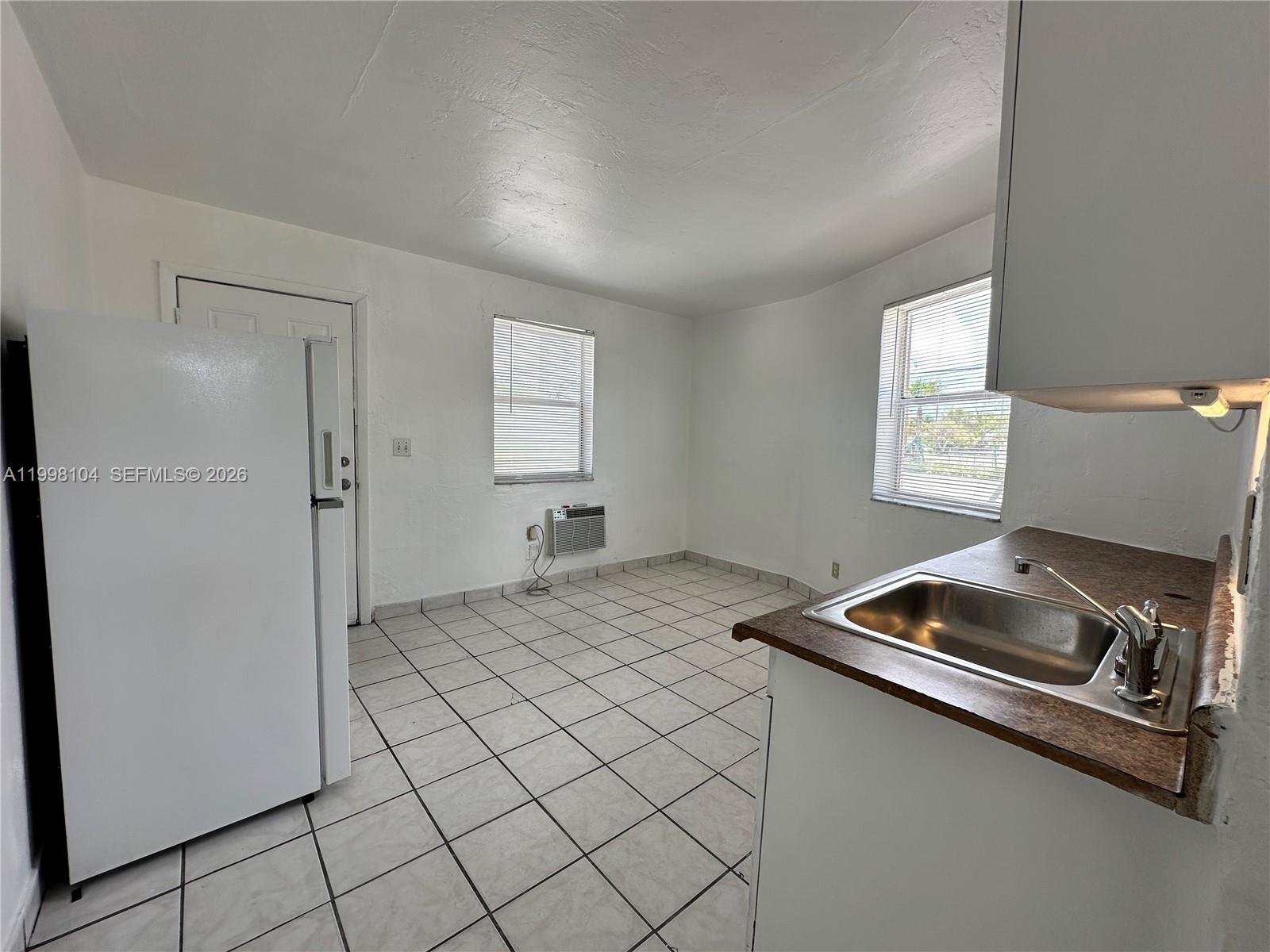 A kitchen features white walls, tiled floors, a stainless steel sink, and a window unit — 701 NW 7th Ave # 1, Hallandale Beach FL 33009, HALLANDALE BEACH, FL