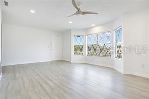 An empty room with light wood-look flooring, white walls, a ceiling fan, and bay windows — 5407 HANSEL AVENUE UNIT G12, ORLANDO, FL