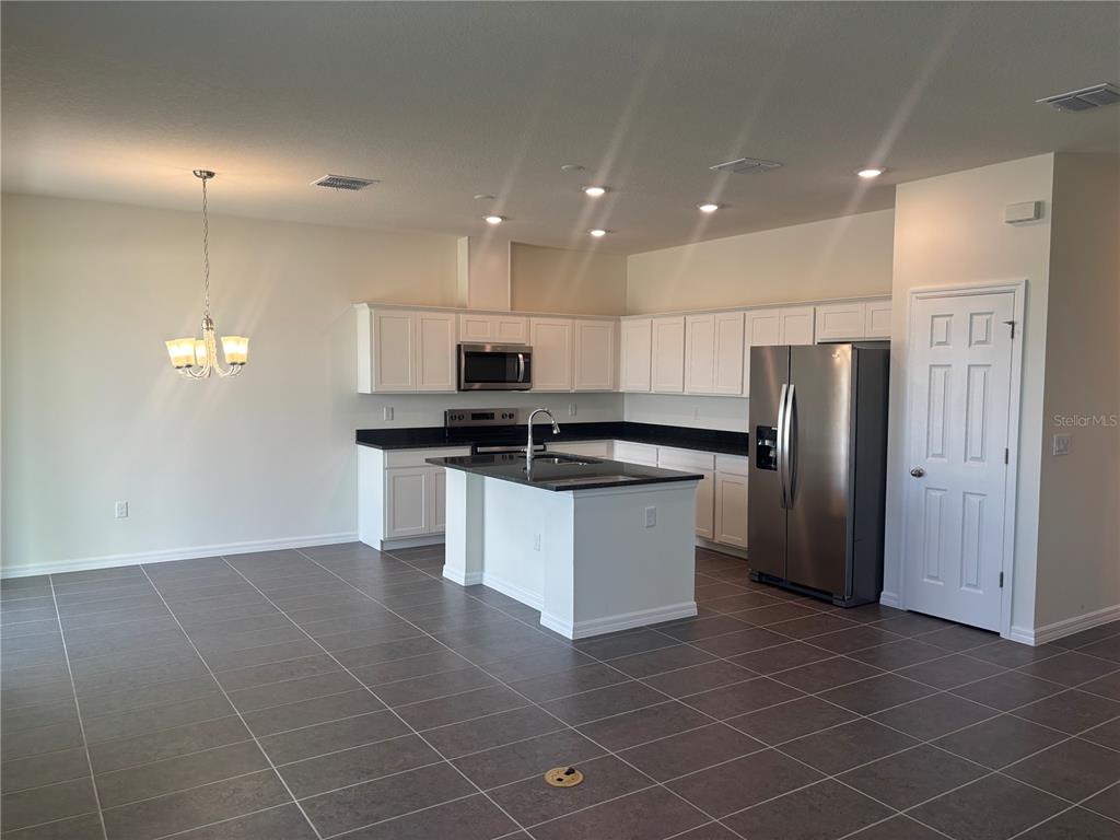 A kitchen features white cabinets, black countertops, a central island, and stainless steel appliances — 2347 SELENIA STREET, LAKE ALFRED, FL
