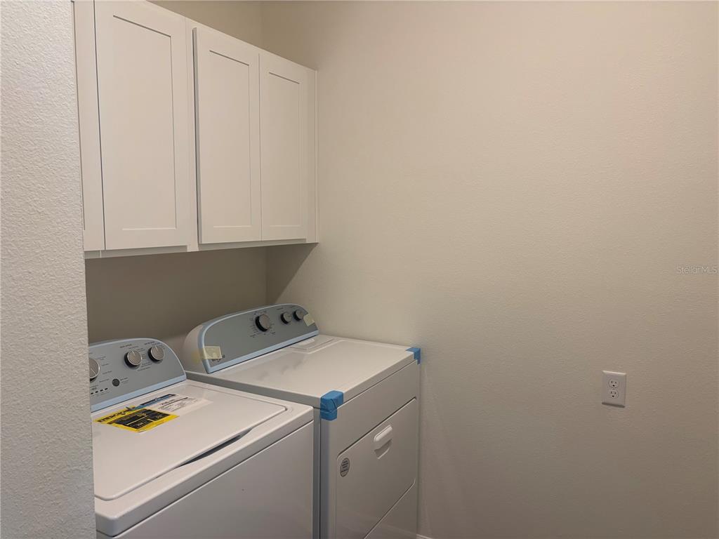 A laundry room features white cabinets above a washer and dryer set — 2347 SELENIA STREET, LAKE ALFRED, FL