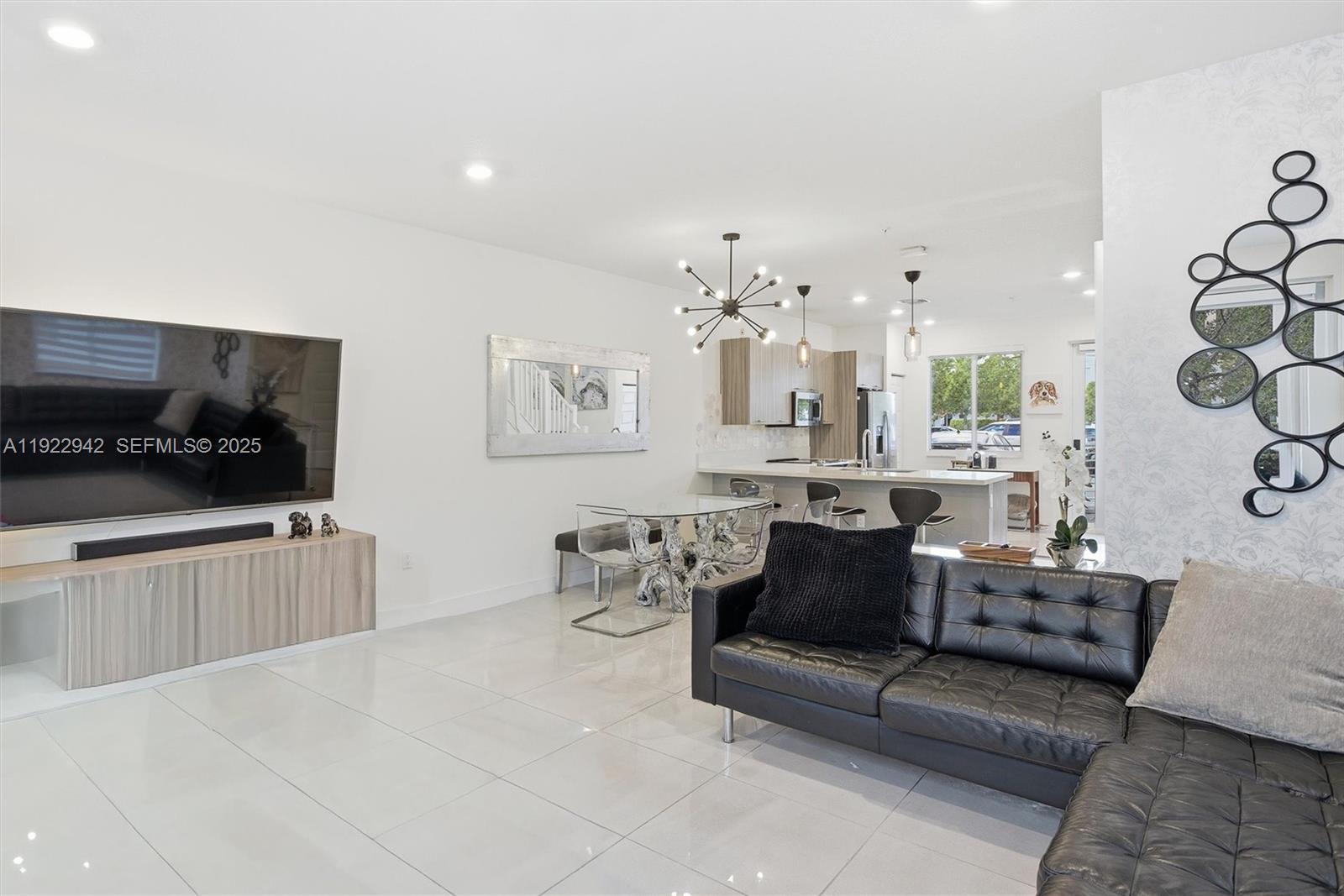 A modern open-concept living room and kitchen feature white tile floors and black furniture — 6420 NW 102nd Path # 110, Doral FL 33178, DORAL, FL