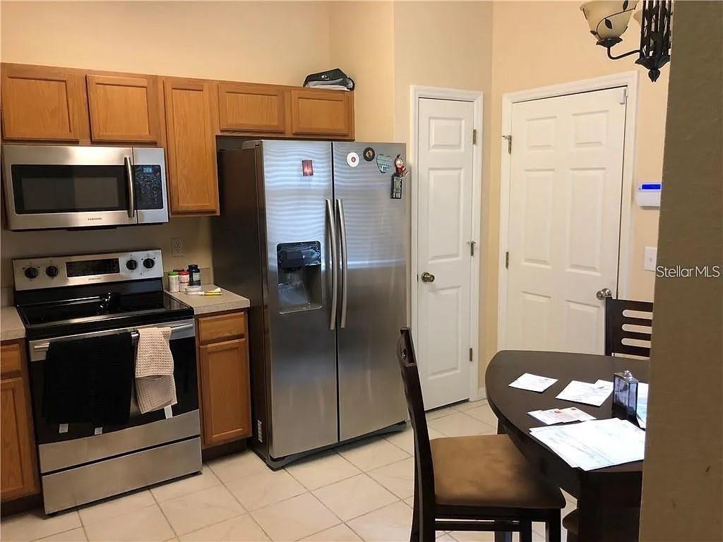 A kitchen features stainless steel appliances, wood cabinets, and a small dining table — 11220 WINDSOR PLACE CIRCLE, TAMPA, FL