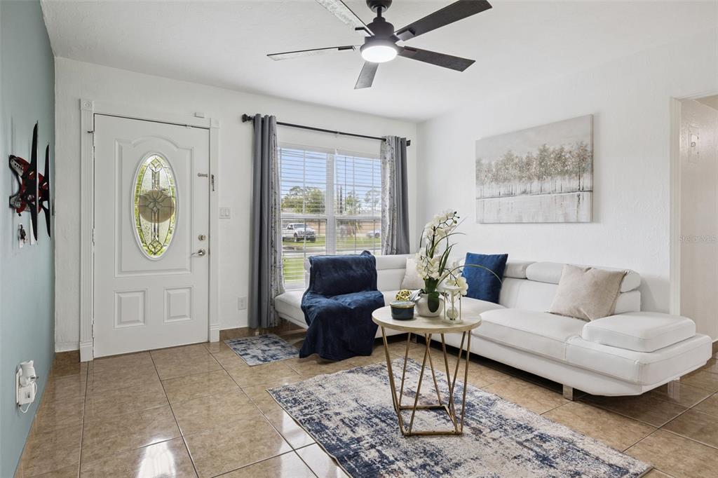 A living room features a white sectional sofa, a round coffee table, and tile flooring — 5907 DAHLIA DRIVE, ORLANDO, FL