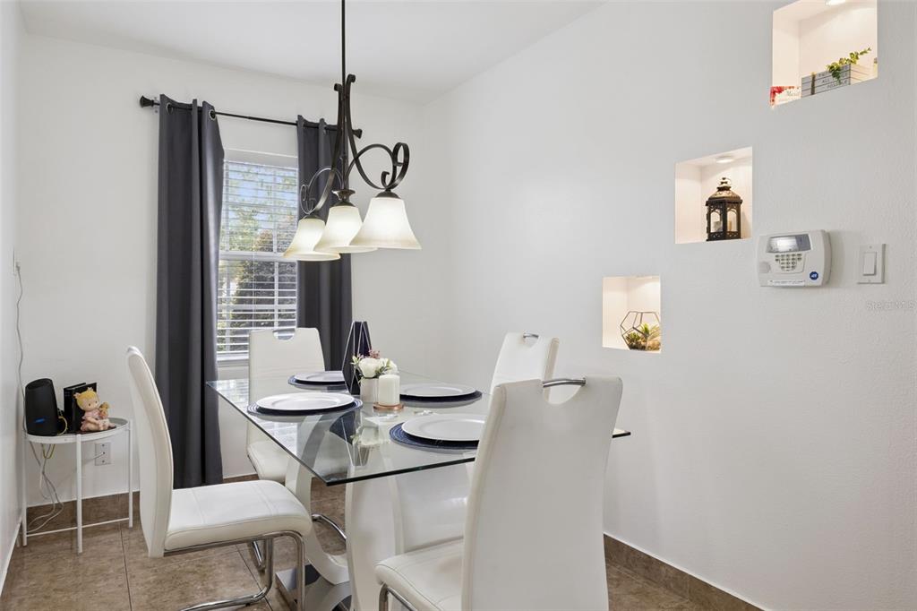 A dining room features a glass table, white chairs, a chandelier, and wall niches — 5907 DAHLIA DRIVE, ORLANDO, FL
