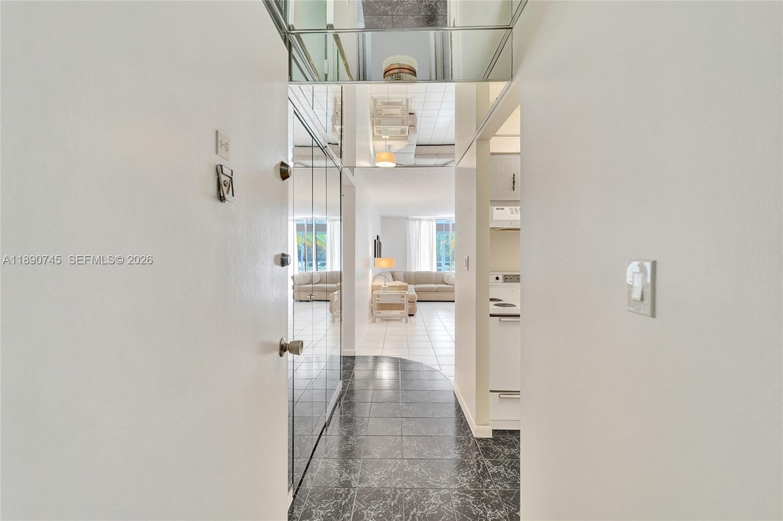 A tiled entryway with mirrored walls leads into a living area with white tile floors — 501 E Dania Beach Blvd # 1G, Dania Beach FL 33004, DANIA BEACH, FL