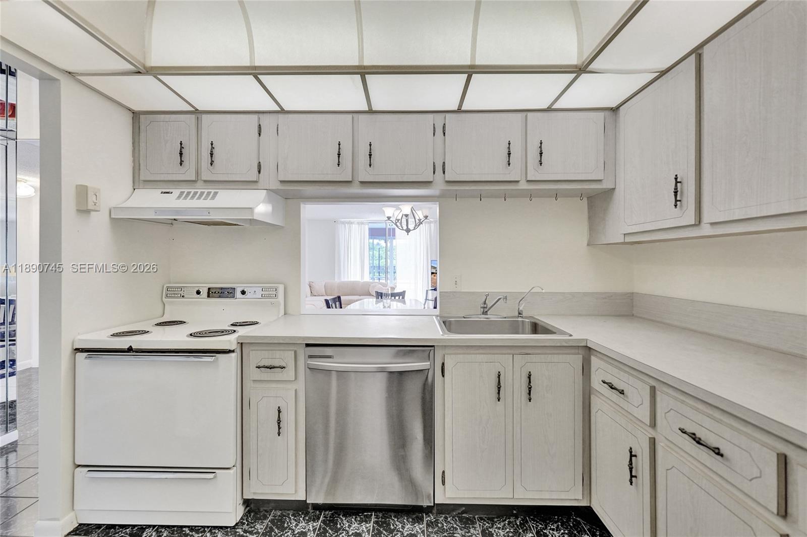 A kitchen features light wood cabinets, a white stove, a stainless dishwasher, and black flooring — 501 E Dania Beach Blvd # 1G, Dania Beach FL 33004, DANIA BEACH, FL