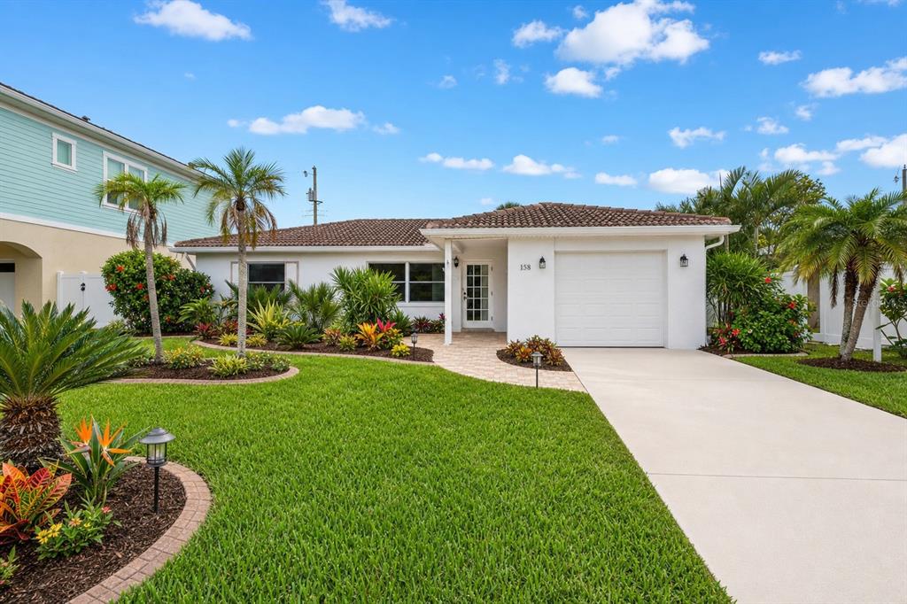 A single-story white house with a tile roof, garage, and landscaped front yard — 158 LIDO DRIVE, ST PETE BEACH, FL