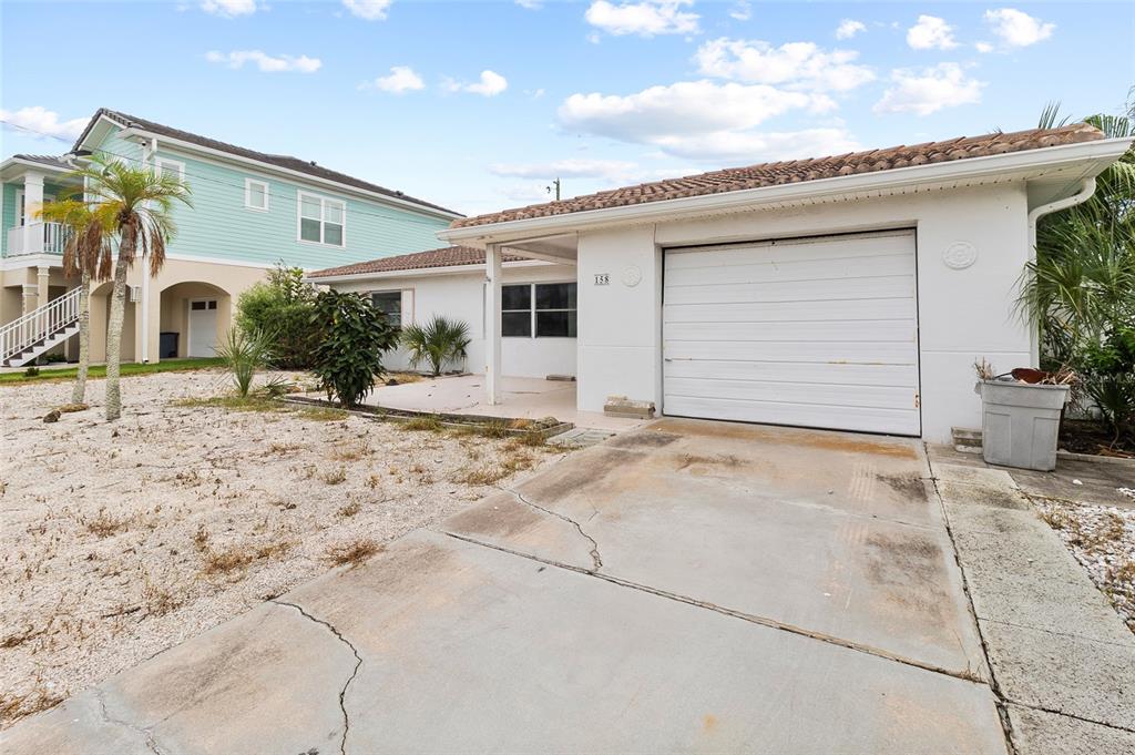 A white single-story house features a garage, a concrete driveway, and a gravel front yard — 158 LIDO DRIVE, ST PETE BEACH, FL