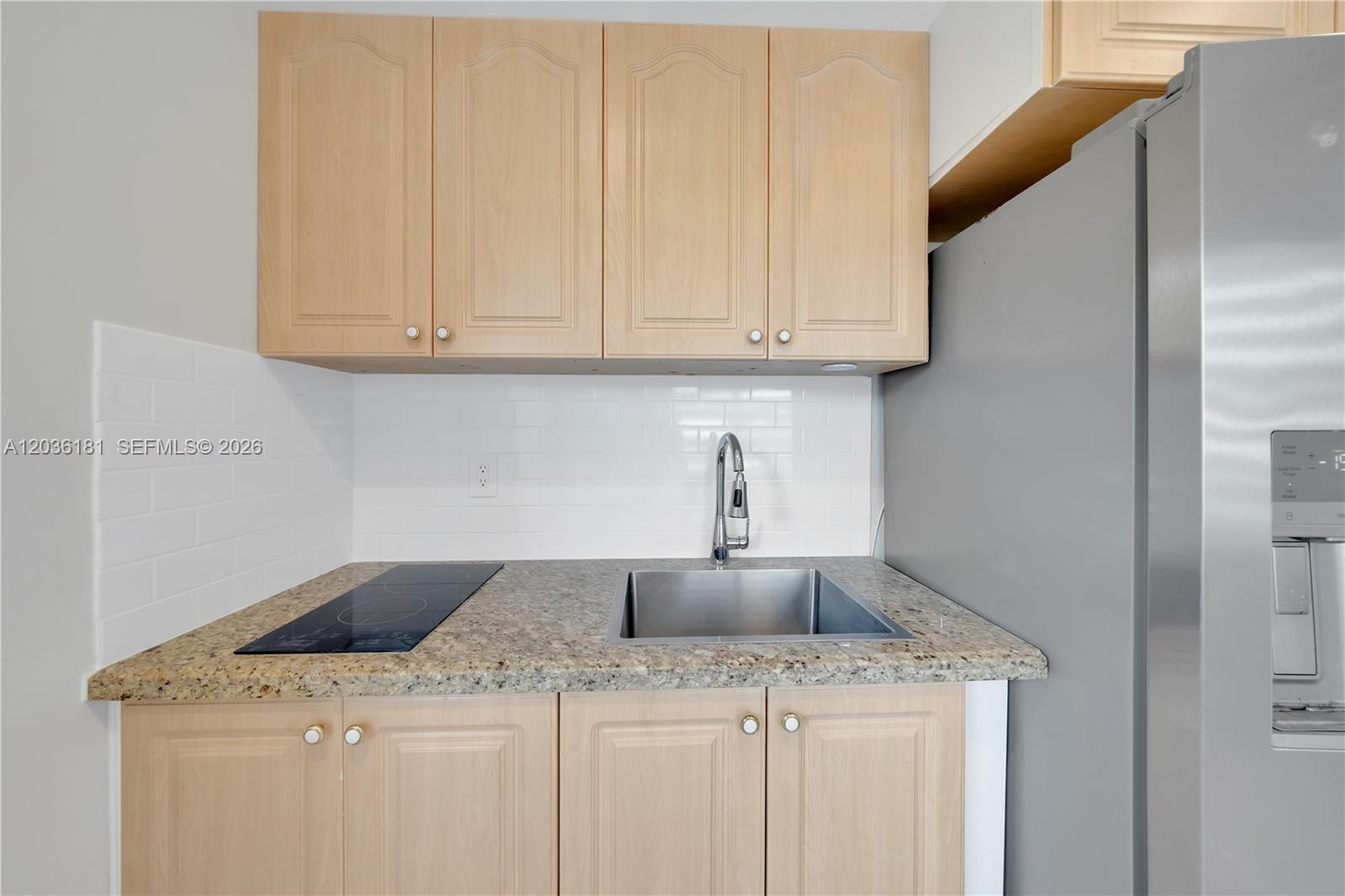 A small kitchen features light wood cabinets, granite countertops, a stainless steel sink, and appliances — 7555 SW 28th St Rd # A, Miami FL 33155, MIAMI, FL