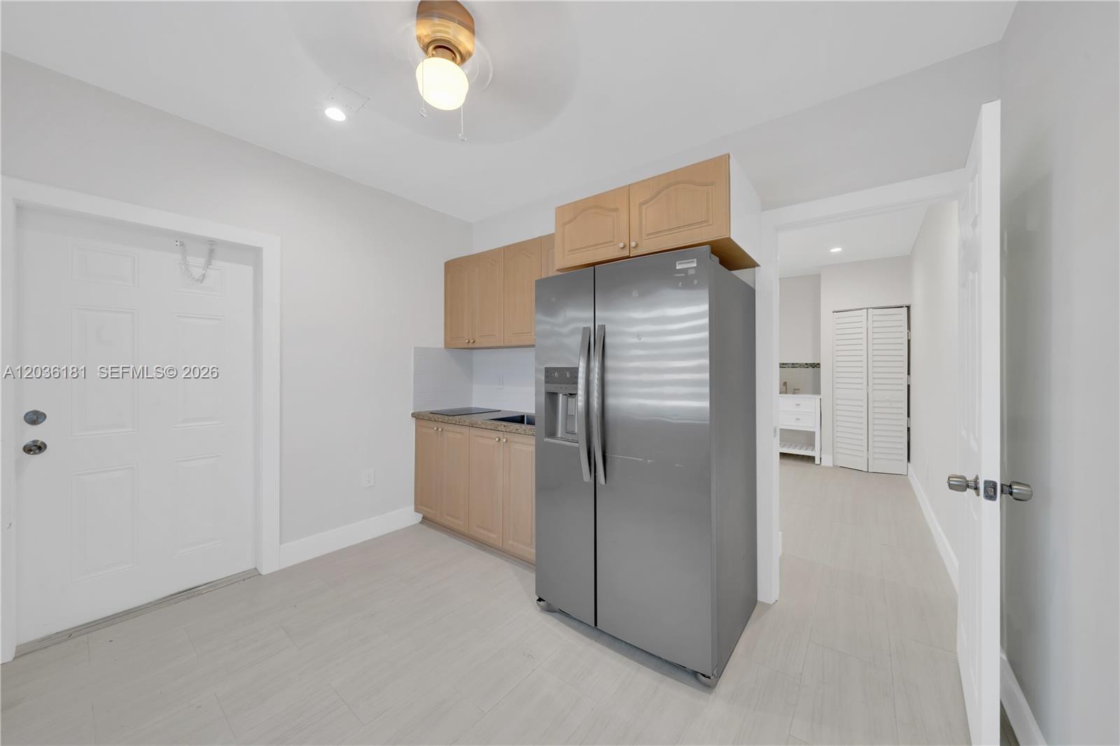 A small kitchen area features light wood cabinets, a stainless steel refrigerator, and tile flooring — 7555 SW 28th St Rd # A, Miami FL 33155, MIAMI, FL