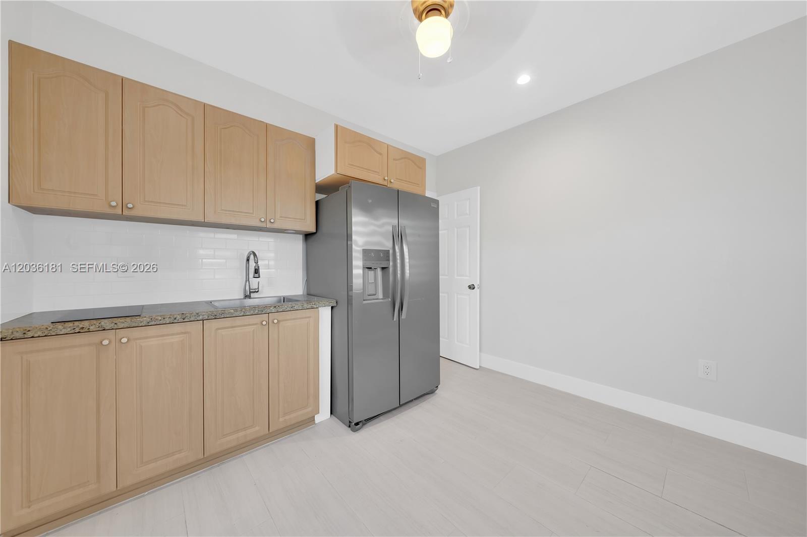 A kitchen features light wood cabinets, a stainless steel refrigerator, and a white subway tile backsplash — 7555 SW 28th St Rd # A, Miami FL 33155, MIAMI, FL
