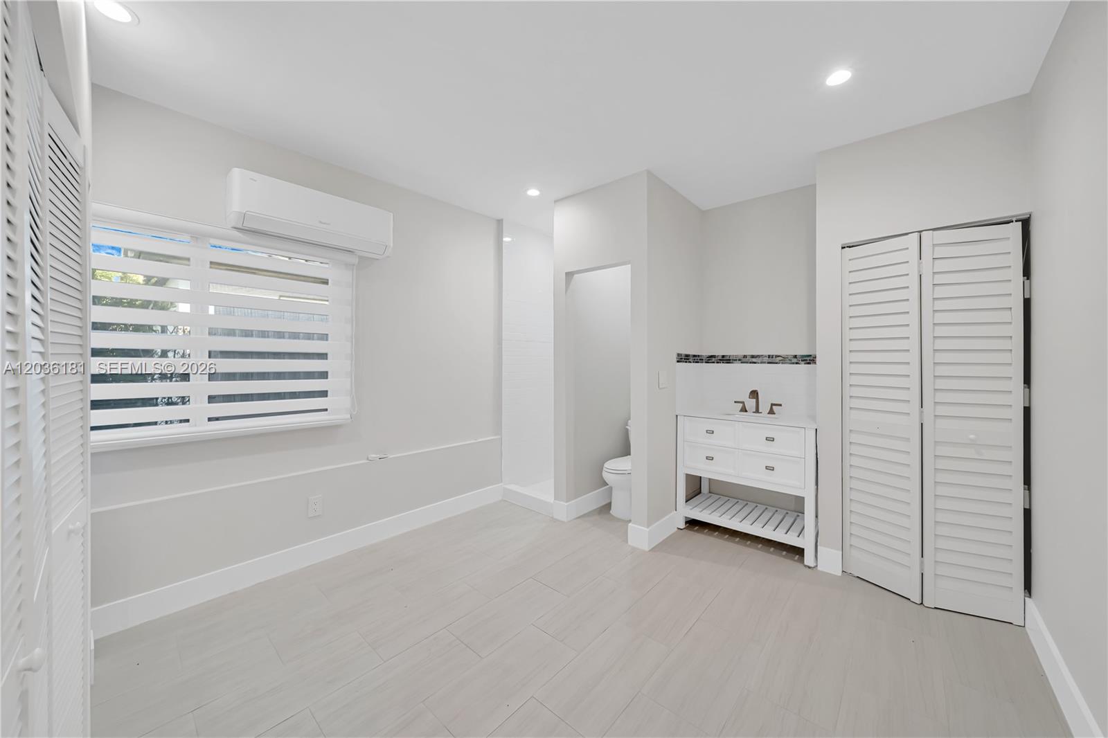 A room with light-colored tile flooring, a vanity, a toilet, and a wall-mounted air conditioner — 7555 SW 28th St Rd # A, Miami FL 33155, MIAMI, FL