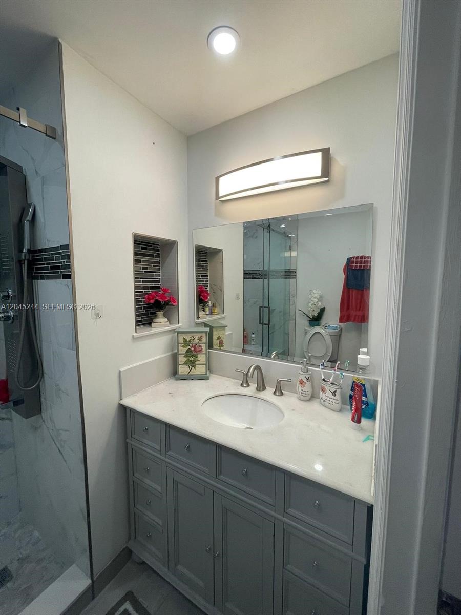 A bathroom features a gray vanity with a white countertop, a mirror, and a shower — 13302 SW 152nd St # 3008, Miami FL 33177, MIAMI, FL