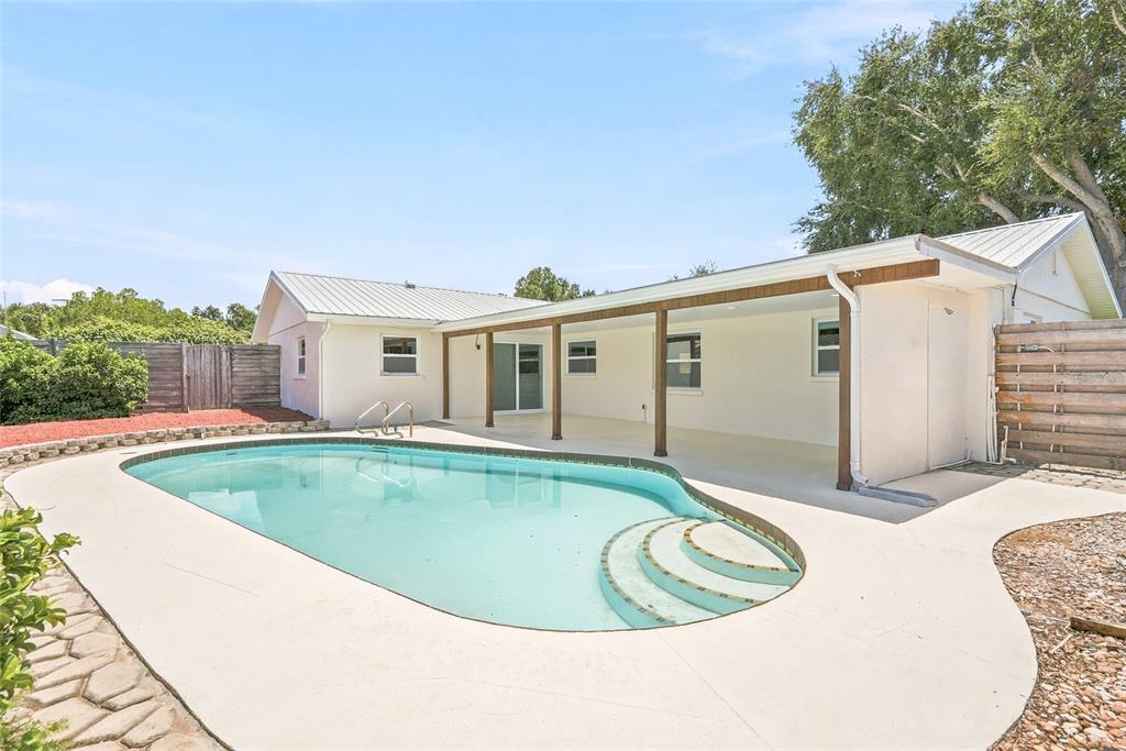 A backyard swimming pool sits on a concrete patio next to a single-story house — 5116 18TH AVENUE W, BRADENTON, FL