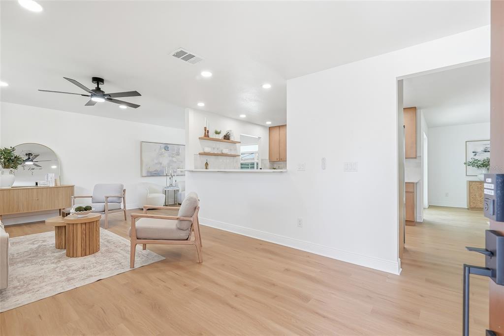 A living room features light wood flooring, a grey sofa, two armchairs, and a ceiling fan — 5116 18TH AVENUE W, BRADENTON, FL